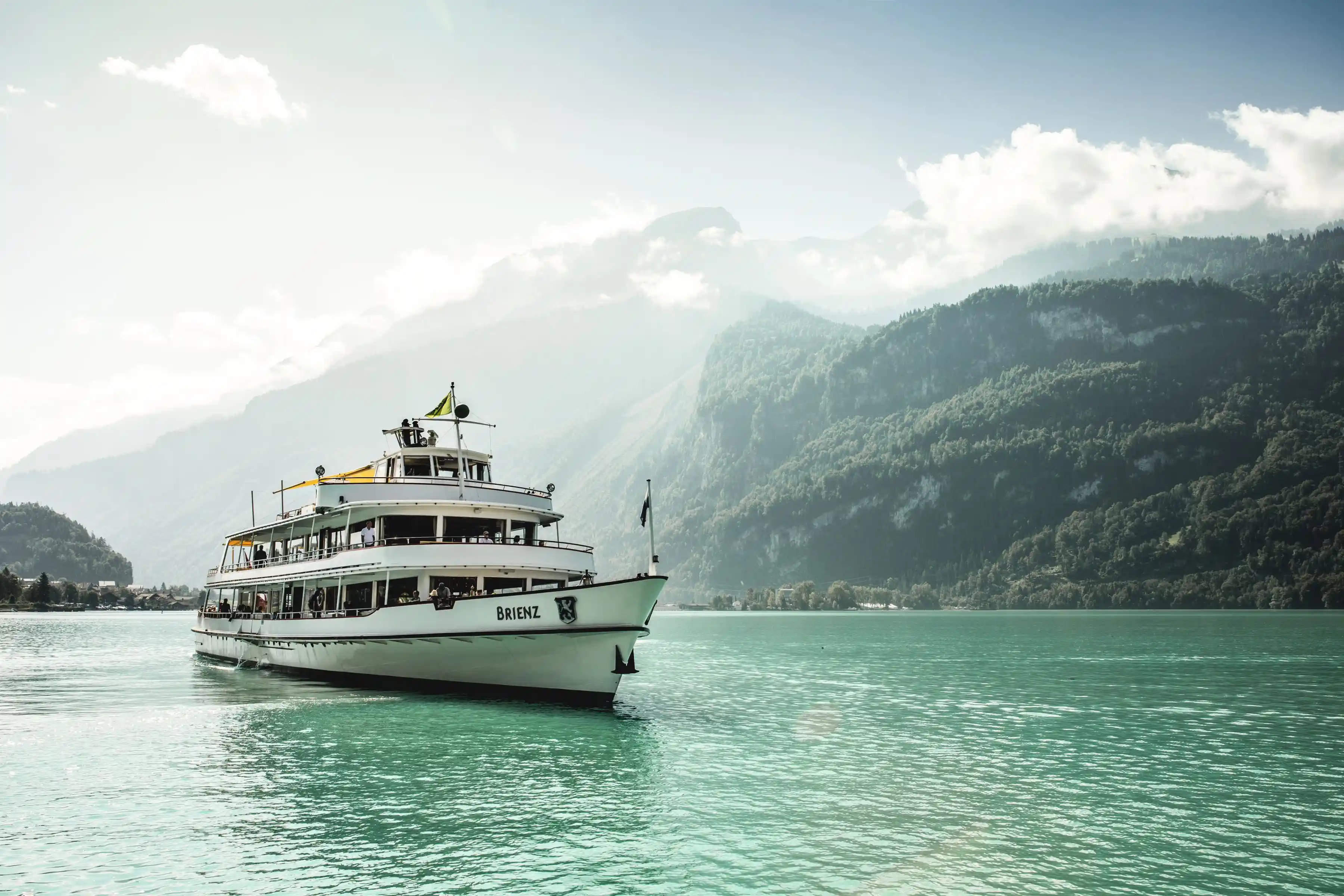 A white cruise ship sailing through Lake Brienz that one can ride with the Swiss Travel Pass, highlighting that it is one of the Hidden Gems with Swiss Travel Pass