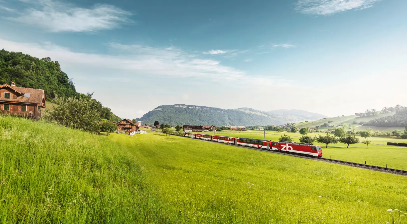 A scenic Swiss train passing through green meadows and alpine villages, showcasing travel experiences among the hidden gems of Lucerne.