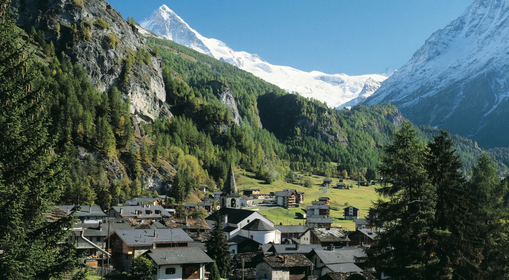 Swiss countryside in spring with wildflowers blooming in bright colors beneath freshly thawed mountains, emphasizing that the best time to visit Switzerland is when spring blossoms 