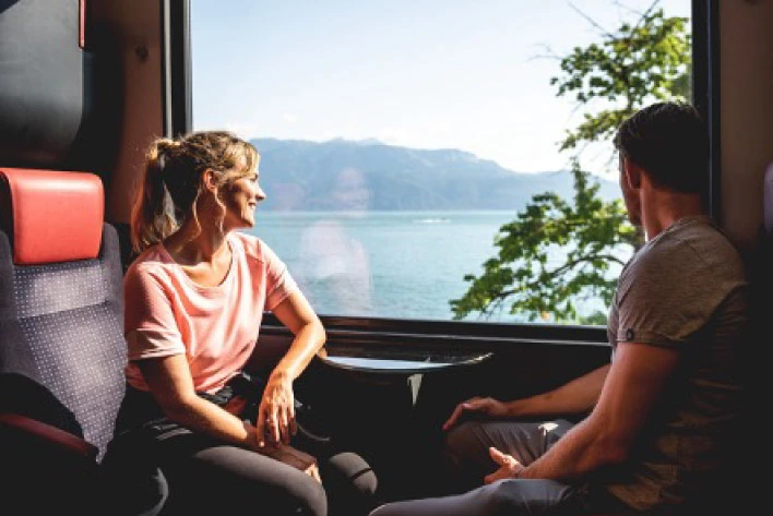 Two people holding Swiss Pass sitting and enjoying the view from a train in Interlaken, Switzerland