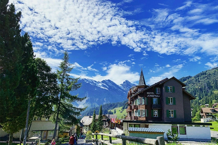 People Walking in Front of Hotel Jungfrau, Switzerland with a Mountain View