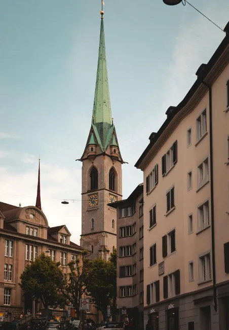 A picturesque view of the Fraumünster Church's iconic green tower, rising above the historic buildings of Zurich