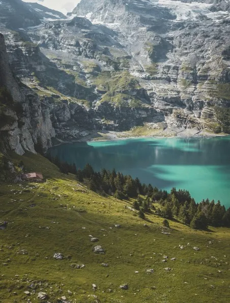 Oeschinen Lake in Kandersteg, Switzerland, featuring stunning turquoise waters surrounded by majestic mountains and lush greenery.