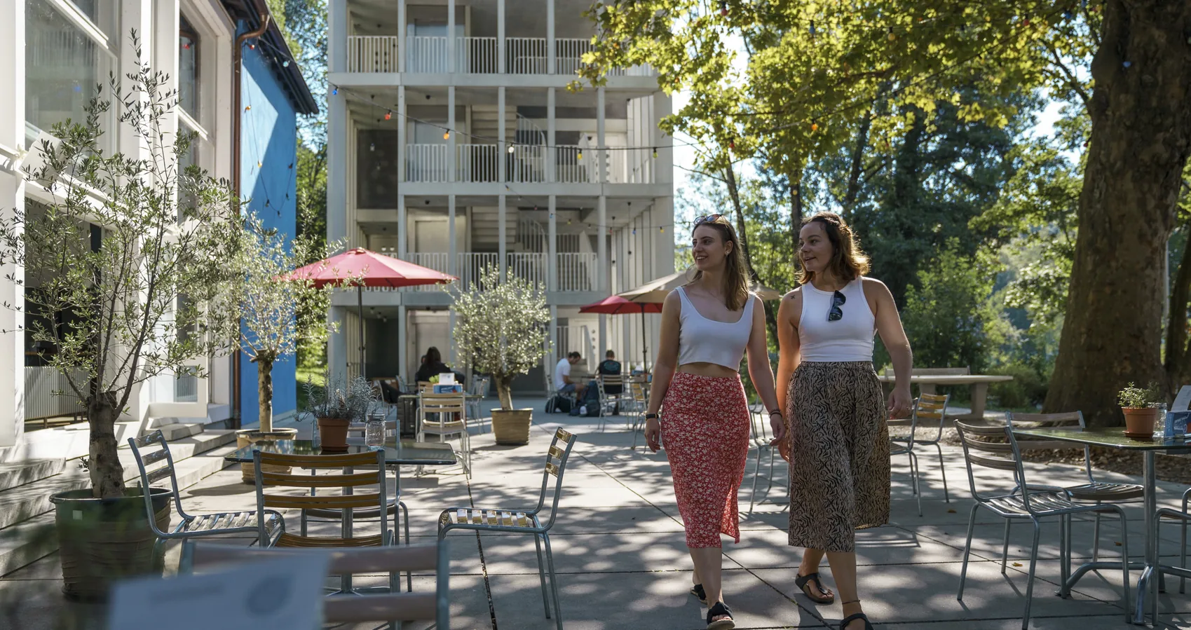 Two women walking through the sunny outdoor terrace of the Bern Youth Hostel in Switzerland